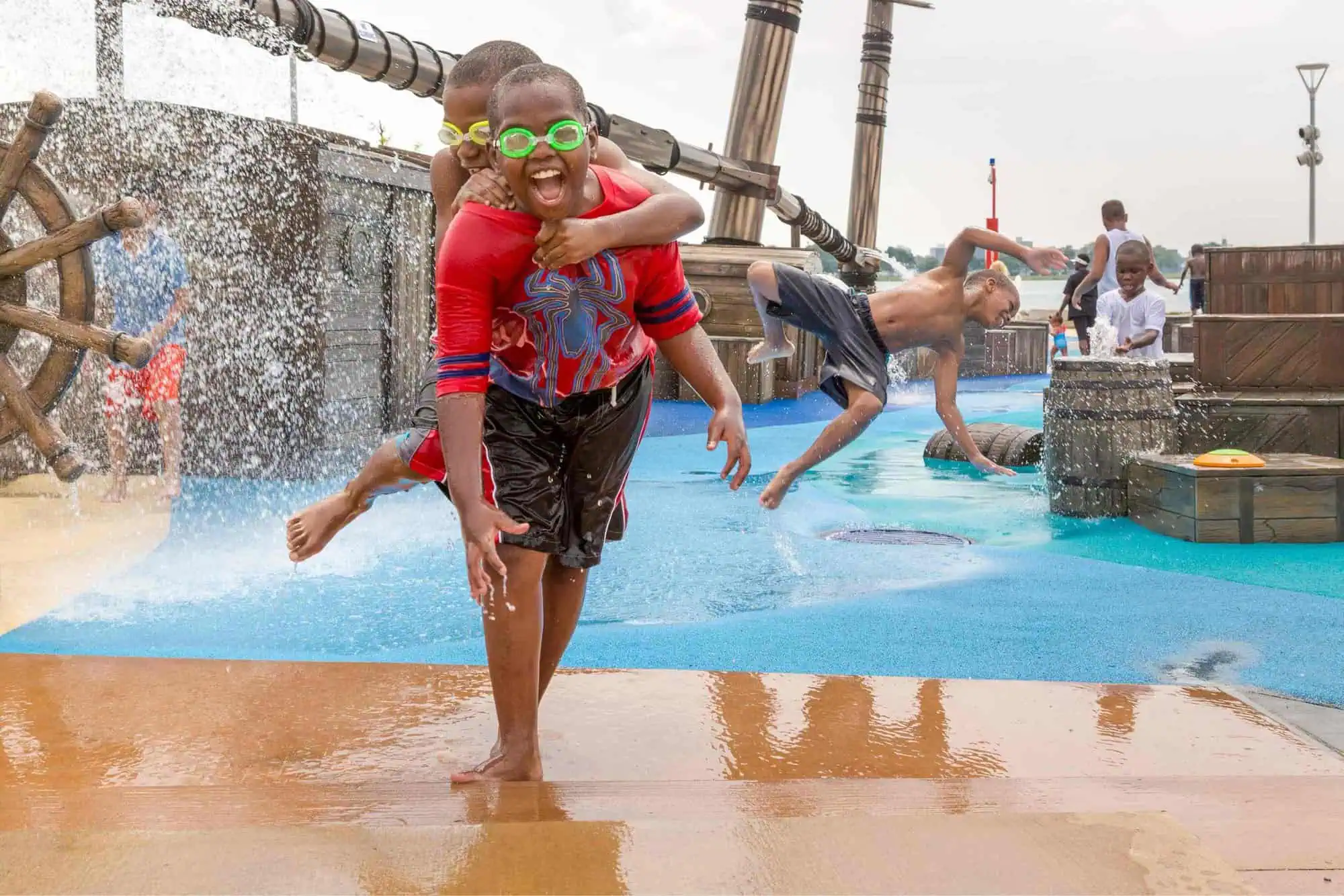 Two boys playing in a waterpark wearing swimming goggles.